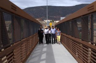 Karen walking across a bridge with community members.